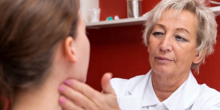 Ärztin tastet die Lymphknoten am Hals einer jungen Frau ab.