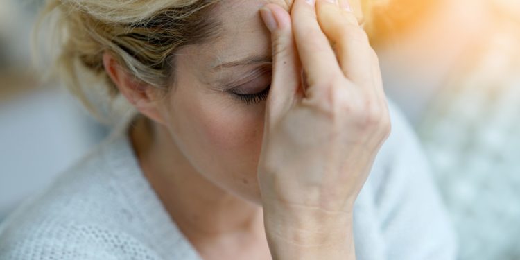 Eine von Migräne geplagte Frau massiert ihre Stirn