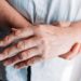 Ältere Frau hält ihr von Rheuma-Schmerzen geplagtes Handgelenk