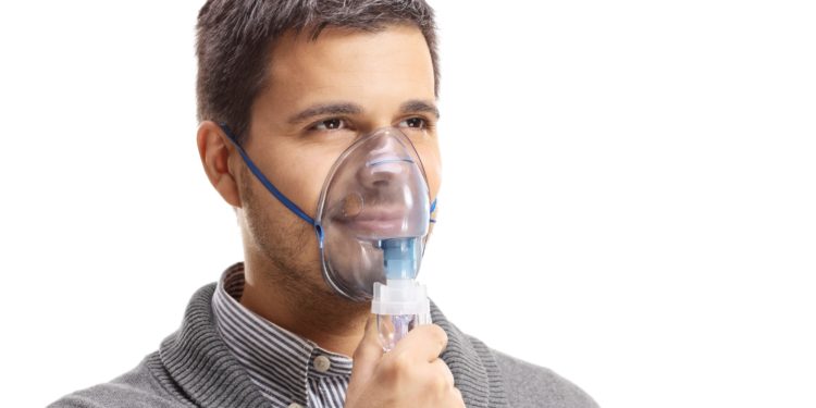 Ein Mann mit einer Sauerstoffmaske über Nase und Mund.