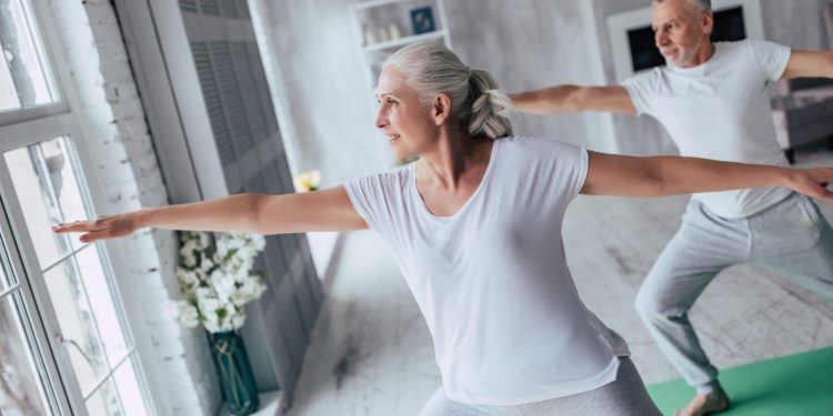 Ein älteres Paar führt zu Hause Gymnastikübungen durch. 