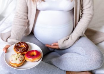 Eine schwangere Frau mit einem Teller voller Donuts