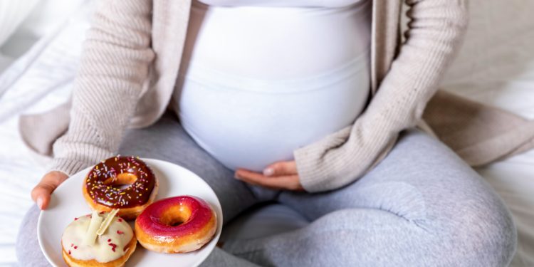 Eine schwangere Frau mit einem Teller voller Donuts