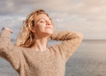 Eine Frau steht am Strand und genießt die Sonne.