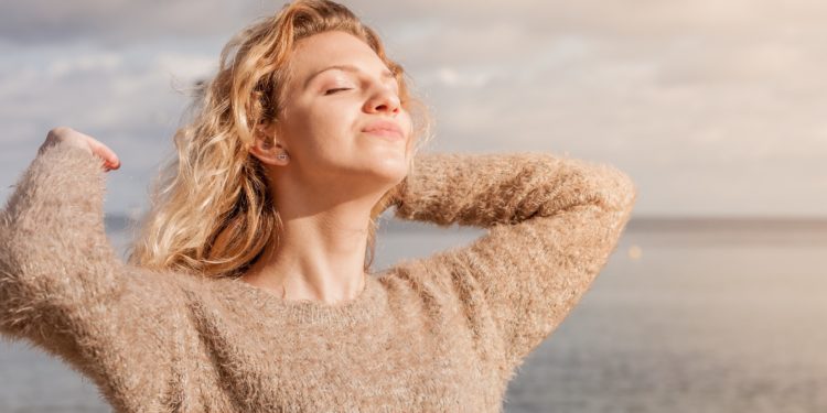 Eine Frau steht am Strand und genießt die Sonne.