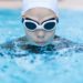 Eine Frau mit Schwimmbrille und Schwimmkappe beim Brustschwimmen.