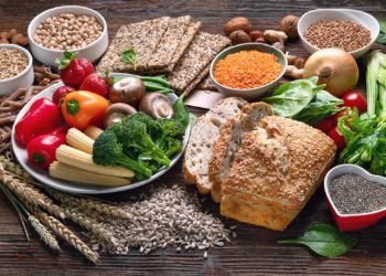 Verschiedene Lebensmittel wie Obst, Gemüse, Knäckebrot und Vollkornnudeln auf einem Tisch