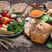 Verschiedene Lebensmittel wie Obst, Gemüse, Knäckebrot und Vollkornnudeln auf einem Tisch