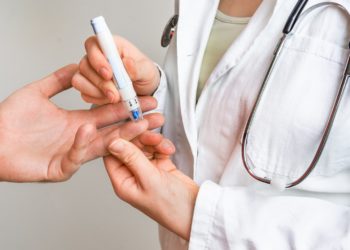 Ärztin misst bei einem Patienten den Blutzucker am Finger