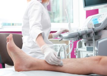 Ärztin führt bei einem Patienten eine Ultraschalluntersuchung des Beins durch