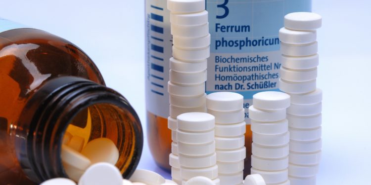 Gestapelte Schüßler-Salz-Tabletten mit Schüßler-Salz-Flasche Ferrum Phosphoricum