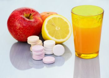 Zwei Äpfel, eine halbe Zitrone, einige Vitamintabletten und ein Glas Orangensaft