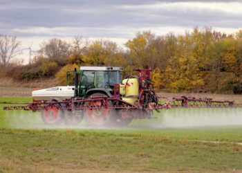 Traktor mit Feldspritze beim Ausbringen von Pflanzenschutzmittel