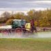 Traktor mit Feldspritze beim Ausbringen von Pflanzenschutzmittel