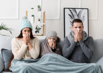 Eltern sitzen mit ihrem Kind auf dem Sofa - alle drei erkältet.