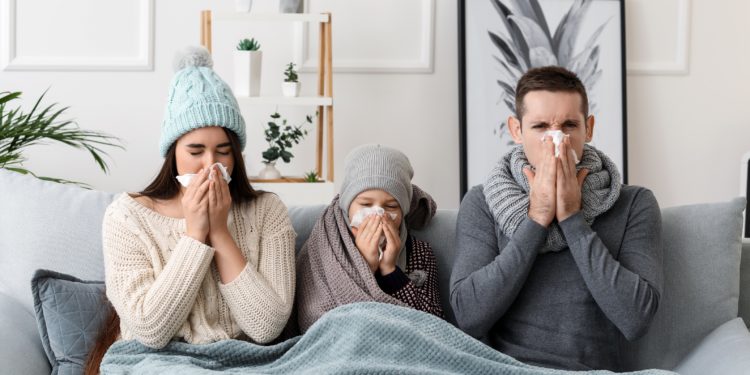 Eltern sitzen mit ihrem Kind auf dem Sofa - alle drei erkältet.