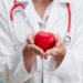 Arzt hält ein rotes Herz in seinen Händen