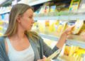 Eine Frau nimmt sich eine Käse-Packung aus einem Regel in einem Supermarkt.