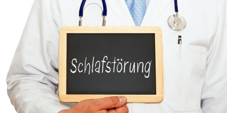 Arzt mit einer Schiefertafel, auf die das Wort Schlafstörung geschrieben ist