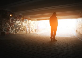 Ein Mann steht in einem mit Graffiti besprühten Tunnel.