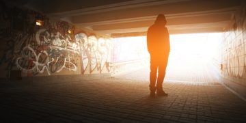 Ein Mann steht in einem mit Graffiti besprühten Tunnel.