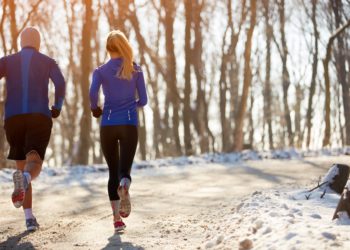 Eine Frau und ein Mann joggen in winterlicher Natur