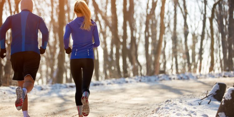 Eine Frau und ein Mann joggen in winterlicher Natur