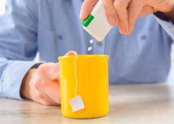 Mann gibt Süßstoff in seine Teetasse