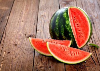 Eine Wassermelone mit zwei herausgeschnittenen Teilen auf einem Holztisch