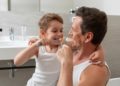 Vater und Sohn putzen gemeinsam Zähne.