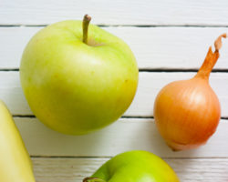 Ein Apfel und eine Zwiebel vor einem weißen Hintergrund.