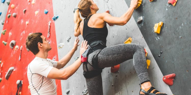 Eine Frau klettert eine Kletterwand in einer Halle hoch.