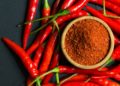 Rote Chilischoten und Chiliflocken auf schwarzem Hintergrund