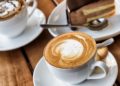 Zwei Tassen Kaffee und ein Stück Torte auf einem Holztisch