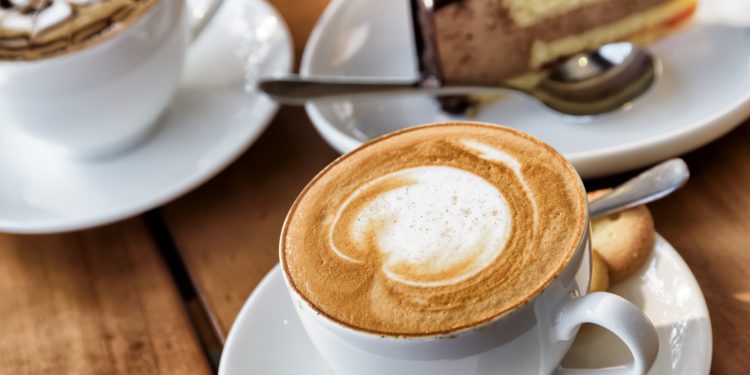 Zwei Tassen Kaffee und ein Stück Torte auf einem Holztisch