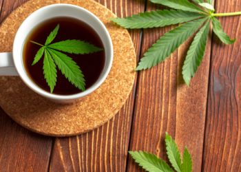 Cannabis-Kräutertee und Hanfblätter auf einem hölzernen Tisch