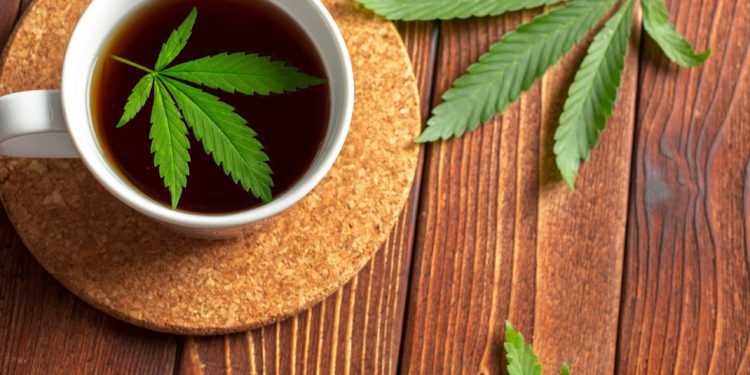 Cannabis-Kräutertee und Hanfblätter auf einem hölzernen Tisch