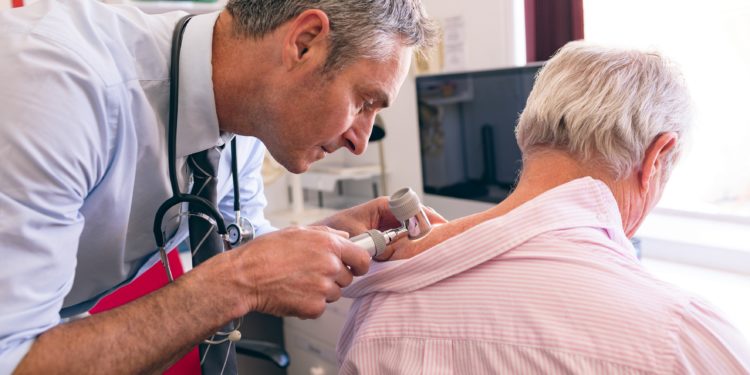 Hautarzt untersucht älteren Patienten auf Anzeichen für Hautkrebs