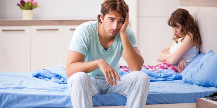Lustloser Mann sitzt im Bett neben frustrierter Frau