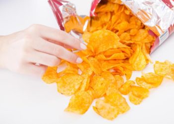 Eine Hand greift in eine Chipstüte.