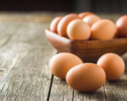 Eier in einer Holzschale und auf einem Holztisch