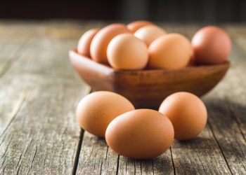 Eier in einer Holzschale und auf einem Holztisch