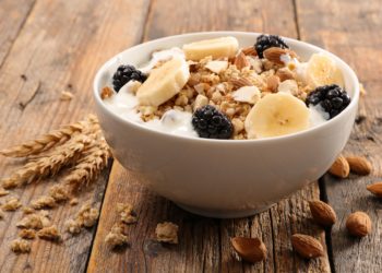Eine Schüssel mit Müsli und Früchten auf einem Holztisch