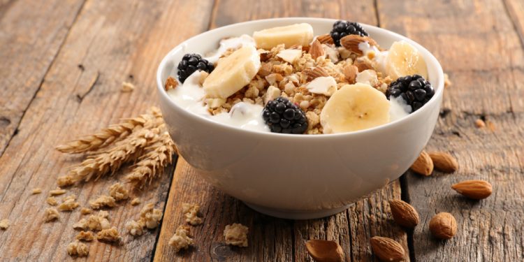 Eine Schüssel mit Müsli und Früchten auf einem Holztisch