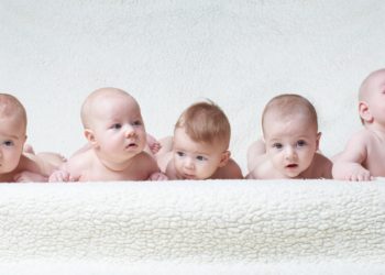 Mehrere auf dem Bauch liegende Babys vor einem hellen Hintergrund
