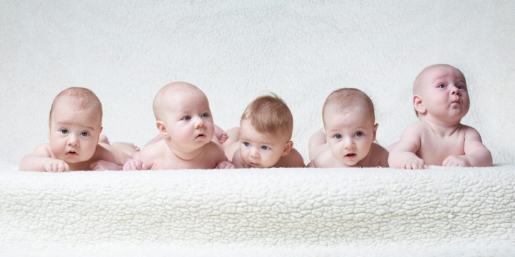Mehrere auf dem Bauch liegende Babys vor einem hellen Hintergrund