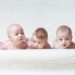 Mehrere auf dem Bauch liegende Babys vor einem hellen Hintergrund