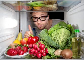 Mann öffnet seinen Kühlschrank mit gesunden Lebensmitteln.