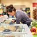 Frau holt Ware aus einer Tiefkühltheke im Supermarkt