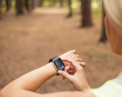Frau guckt auf ihren Schrittzähler am Handgelenk